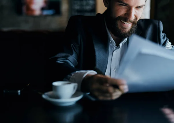 Homem de negócios sentado a uma mesa em um café documentos de trabalho copo de café oficial — Fotografia de Stock