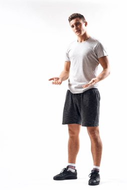 Hafif bir geçmişi olan atletik bir adam tam boy ve koşu şortu spor ayakkabısı tişörtü giyiyor.