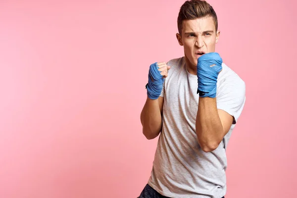 Guy in blue gloves on a pink background are boxing in a white t-shirt cropped view — Stock Photo, Image