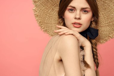 Hasır şapkalı bir kızın portresi pembe arka plan duyguları yakın plan güzel yüz modeli örgüler.