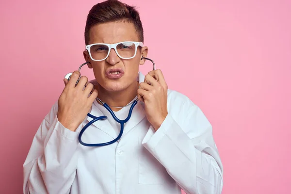 Jeune médecin avec un stéthoscope et des lunettes sur fond rose infirmière stagiaire modèle — Photo