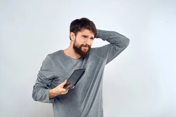 Een man met een baard met een tablet in zijn handen een grijze jas technologie internet licht achtergrond — Stockfoto