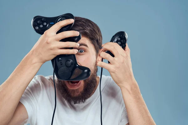 Hombre celebración gamepads juegos estilo de vida tecnología consola emociones blanco camiseta azul fondo —  Fotos de Stock