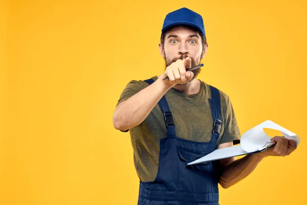 Mann in Arbeitsform dokumentiert Transport-Lieferservice gelben Hintergrund — Stockfoto