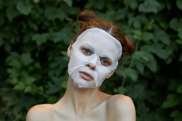 Portrait d'une fille masque cosmétique regarder vers l'avenir et buissons dans la cosmétologie du parc — Photo