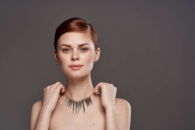 Çıplak omuzları süsleyen güzel bir kadın topuz grisi arka planda saç topladı.