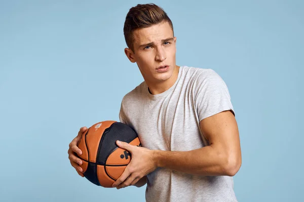 Hombre con una pelota de baloncesto en un fondo azul deporte juego modelo blanco camiseta energía —  Fotos de Stock