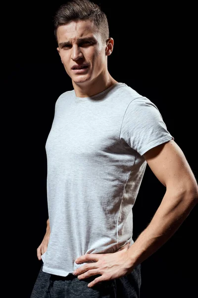 Красивый мужчина в белой футболке на черном фоне надутые мышцы рук спортивная модель обрезанный вид — стоковое фото