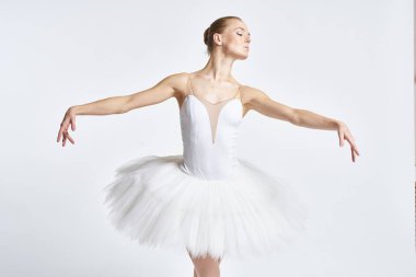 Beyaz etekli balerin dans egzersizi yapıyor. Esnek arka plan.