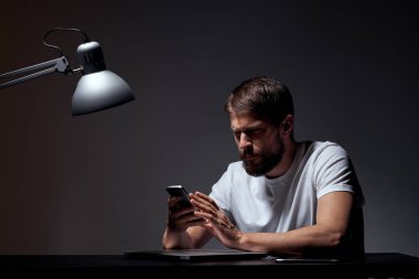 Koyu arka planda cep telefonu olan iş adamı ve demir lamba kesikli iş manzarası