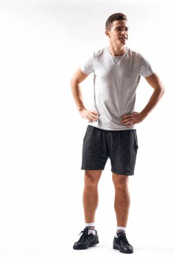 Şortlu ve uzun tişörtlü bir sporcu hafif arka plan üzerinde egzersiz yapar.