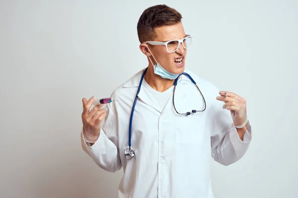 Γιατρός σε ένα ιατρικό φόρεμα με στηθοσκόπιο και γυαλιά σε ένα ελαφρύ φόντο περικοπεί πορτρέτο άποψη — Φωτογραφία Αρχείου