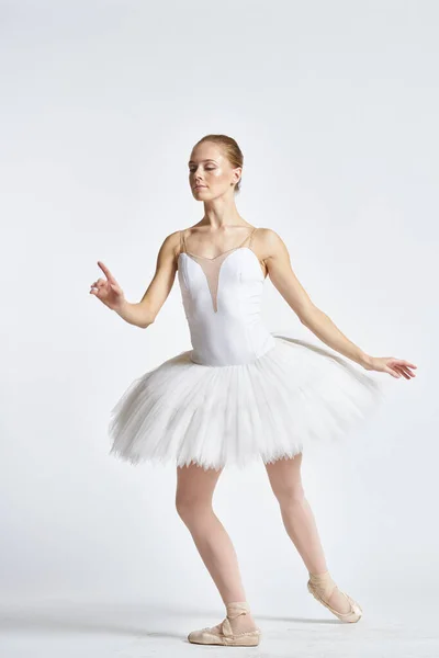 Bailarina em um tutu branco realizando dança exercício flexibilidade luz fundo — Fotografia de Stock