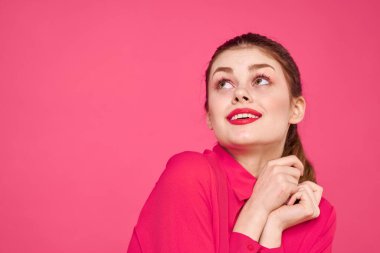 Pembe tişörtlü çekici bir kız parlak makyajlı kırmızı dudaklar ellerle işaret ediyor Boşluğu kopyala