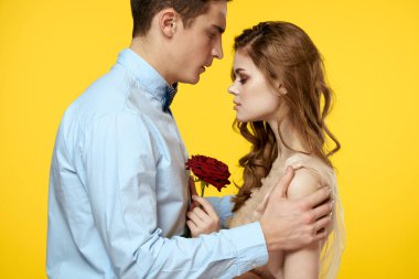 Kırmızı çiçeğe aşık romantik bir çift. Birbirlerine sarılıyorlar. Kırpılmış manzara.