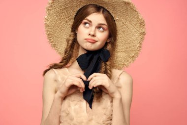 Hasır şapkalı bir kızın portresi pembe arka plan duyguları yakın plan güzel yüz modeli örgüler.