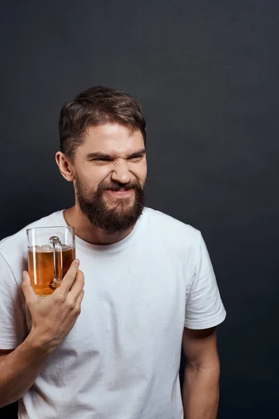 Мужчина с кружкой пива в руках эмоции веселья образ жизни белая футболка темно-изолированный фон — стоковое фото