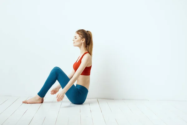 Atletisk kvinna i pose på golvet motion gymnastik prestanda ljus bakgrund — Stockfoto