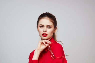 Kırmızı gömlekli şık bir kadın açık arkaplanda eğlenceli duygular parlak makyaj gözlükleri çekici bir görünüş. 