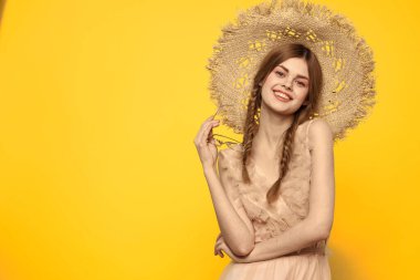 Hasır şapkalı duygusal kız ve sarı arka planda kırmızı örgülü bir elbise.