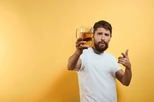 Мужчина с кружкой пива весело алкоголь образ жизни белый футболка желтый изолированный фон — стоковое фото