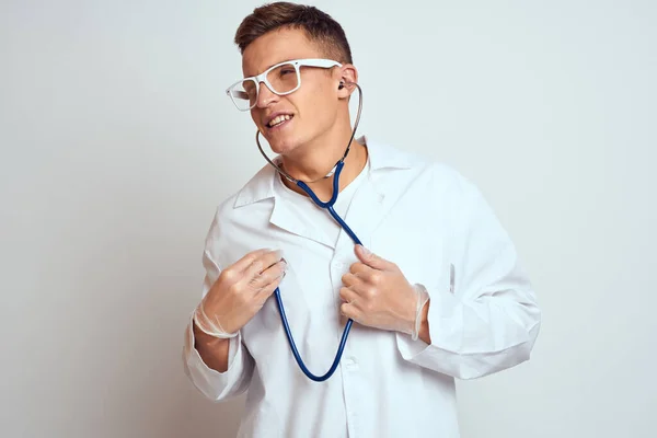 Médecin dans une robe médicale avec un stéthoscope et des lunettes sur un fond clair portrait de vue recadrée — Photo