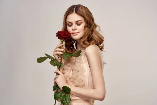 Uroczy model kobieta z czerwoną różą w dłoni i wieczorem makijaż sukienka — Zdjęcie stockowe