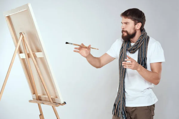 Un uomo artista disegna su un cavalletto una sciarpa bianca t-shirt arte hobby creatività — Foto Stock