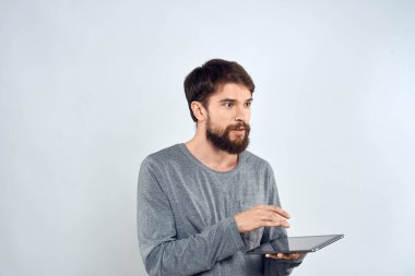 Elinde tablet olan sakallı bir adam. Gri ceketli, teknolojili, internet ışıklı bir arka plan.