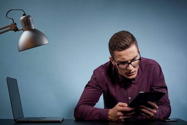 Hombre gerente en la oficina con una tableta en la mano y un ordenador portátil en la mesa — Foto de Stock