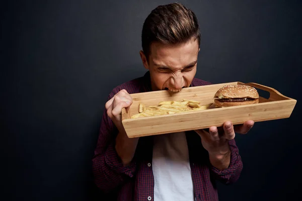 man holding wooden pallet with fast food in his hands diet food hunger lifestyle dark background