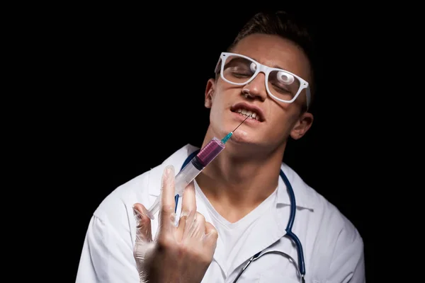 Médecin avec du liquide dans une seringue sur fond noir et un stéthoscope autour du cou vue recadrée — Photo