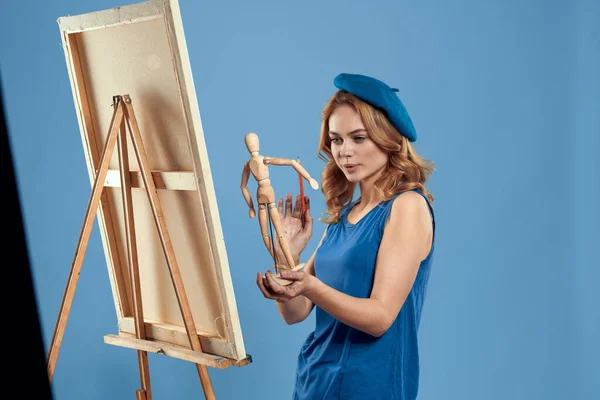 나무로 만든 만네 킨이 젤 미술을 손에 들고 창조적 취미인 푸른 배경을 가진 여성 미술가 — 스톡 사진