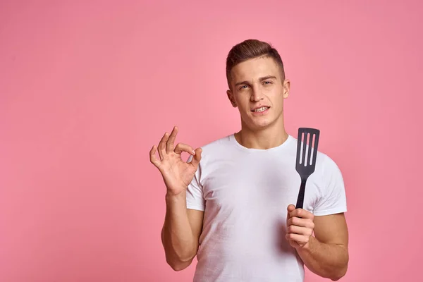 Homem com ferramentas de cozinha em espátula de fundo rosa para cozinhar modelo corte vista — Fotografia de Stock