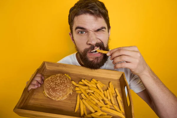 Man with wooden pallet fast food hamburger french fries diet food intake close-up