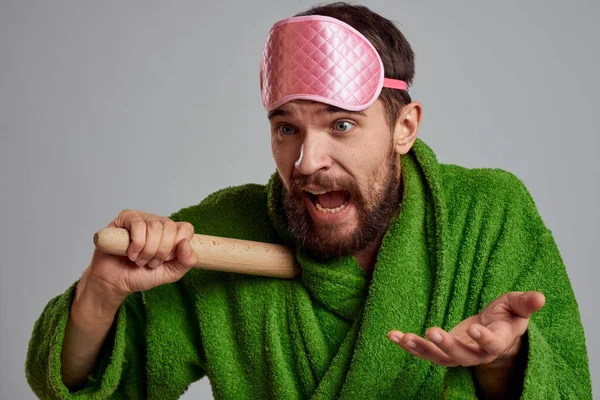 Человек со скалкой в руке зеленый халат розовый сон маска обрезанный вид — стоковое фото