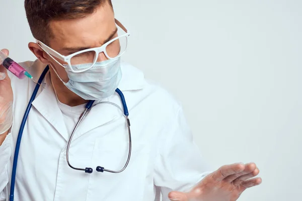 Лікар в медичній сукні зі стетоскопом і окулярами на світлому фоні обрізаний портрет — стокове фото