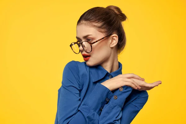Una mujer con una camisa azul y gafas con maquillaje brillante en la cara está haciendo gestos con las manos Copiar espacio — Foto de Stock