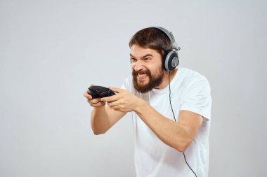 Gamepad 'li kulaklıklı bir adam hobi hayatı tarzı hafif arka planda oynuyor.