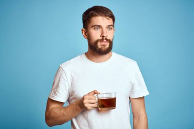 Mavi arka planda bir fincan çayı olan bir adam eğlenceli duygu görüntüsünü kırptı. Boşluğu kopyala