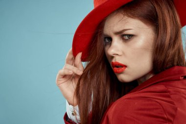 Güzel, zarif, kırmızı dudaklı, şapkalı bir kadın. Yakın plan, göz kamaştırıcı, mavi arka plan.