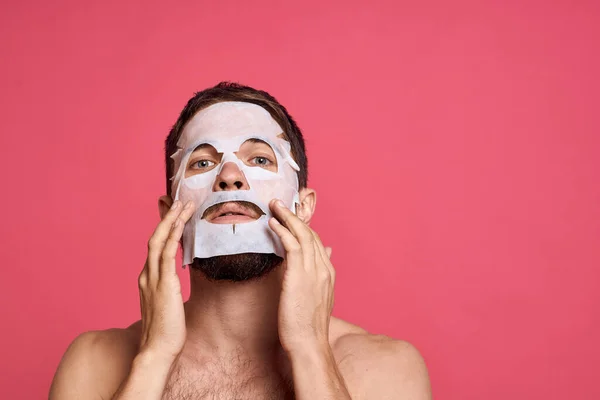 man in cleansing mask on pink background gesturing with hands naked torso cropped view