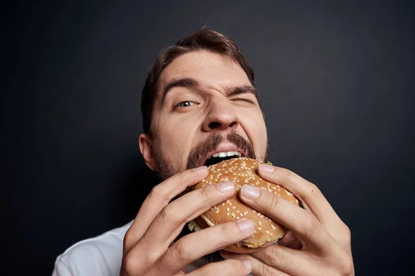 Mann isst Hamburger Fast-Food-Restaurant Gourmet isst dunklen Hintergrund — Stockfoto