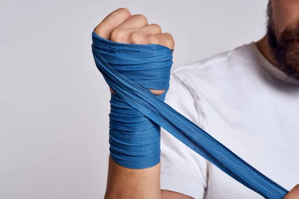 Un hombre ata su mano con vendajes de boxeo en una camiseta blanca —  Fotos de Stock