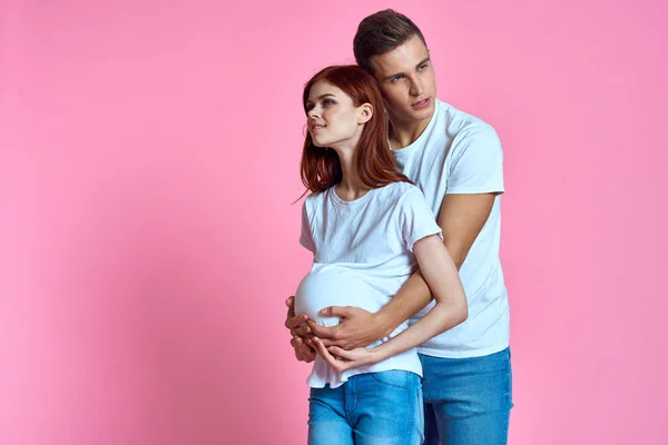 Pregnant mom and happy father on pink background Young family waiting for baby — Stock Photo, Image