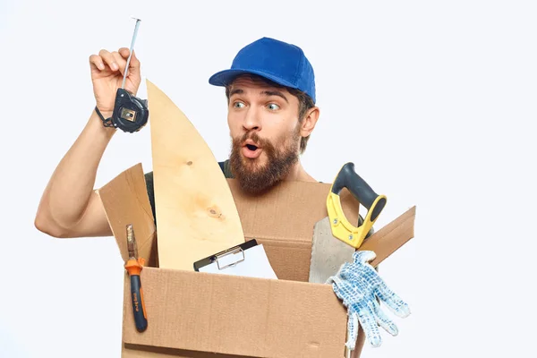 Arbetare man i uniform med en låda i händerna verktyg leverans service ljus bakgrund — Stockfoto