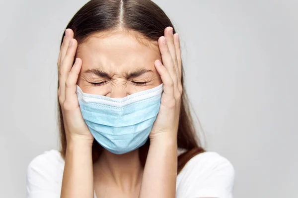 Irritable woman in medical mask squinting her eyes and touching her face with her hands