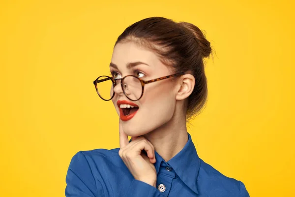 Женщина в синей рубашке и очках с ярким макияжем на лице жестикулирует руками — стоковое фото