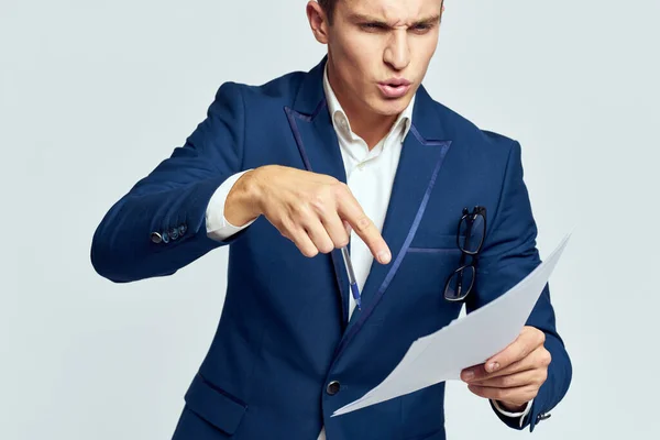 Homme d'affaires dans une veste avec des documents dans ses mains sur un travail de fond léger regard intéressé — Photo