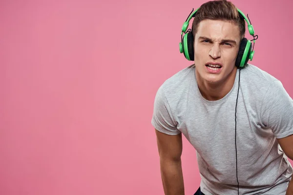 Een man met een joystick in zijn handen koptelefoon spelen spelletjes entertainment levensstijl wit t-shirt roze achtergrond — Stockfoto